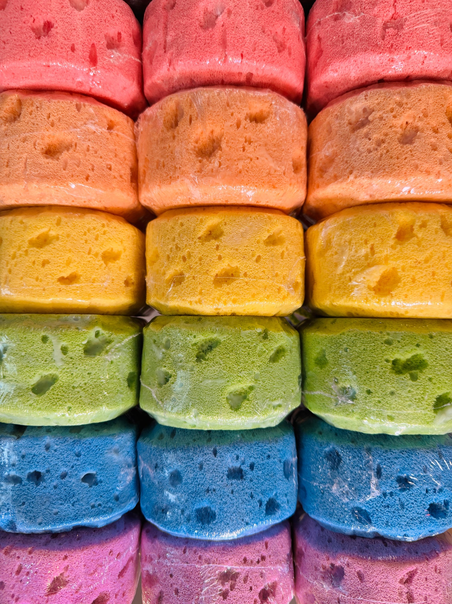 Stack of colorful sponges in various colors including pink, blue, green, yellow, and orange.