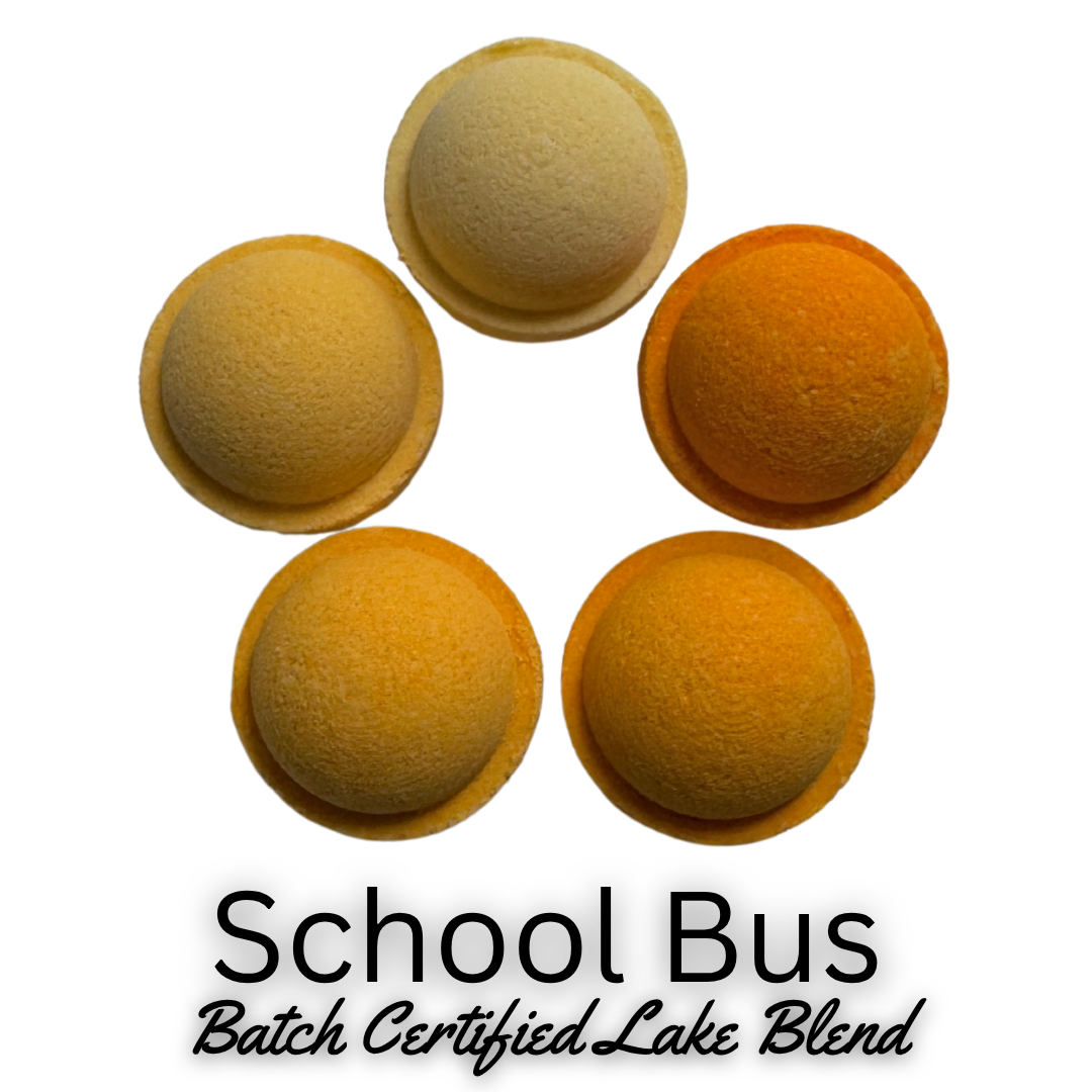 Four oval-shaped bath bomb pieces in yellow, orange, and cream tones arranged in a circle on a white background, with the text 'School Bus Batch Certified Lake Blend' below.